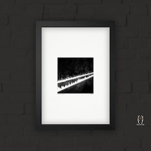 May include: Framed black and white abstract art print. The artwork features two parallel, bright white lines against a dark background, with a textured, blurred effect. The print is in a black frame with a white mat.