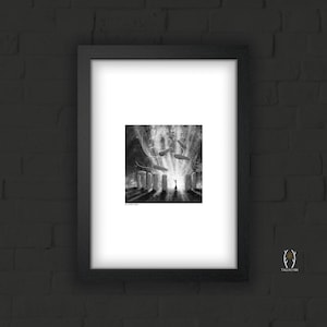 May include: Black and white framed art print depicting a surreal scene with standing stones, floating objects, and a figure with arms raised. The artwork is set against a bright, radiant background, creating a dramatic contrast.