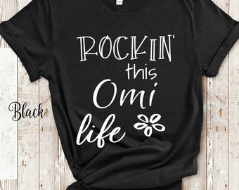 May include: Black t-shirt with white text that reads "Rockin' this Omi life" with a small flower graphic.
