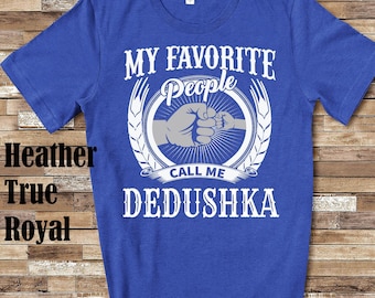 Puede incluir: Una camiseta azul real con un diseño gráfico blanco. El gráfico presenta un choque de puños entre dos manos, una corona de trigo y el texto "My Favorite People Call Me Dedushka".