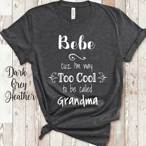 以下が含まれることがあります： 暗いヘザーグレーのTシャツに、白い文字で「Bebe cuz I'm way Too Cool to be called Grandma」と書かれています。
