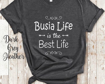 May include: Dark grey heather t-shirt with the text "Busia Life is the Best Life" in white. The shirt is knotted at the bottom. The words "Dark Grey Heather" are written in cursive on the left side.
