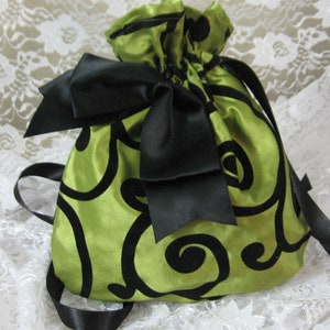 May include: A green satin drawstring bag with a black swirl pattern and a large black satin bow.