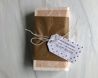May include: A package of Swedish sponge cloths wrapped in brown paper with a white tag that reads "Swedish Sponge Cloths" and includes details about the product, such as "Reusable", "100% Biodegradable", "Machine washable", and "Allow to air-dry".