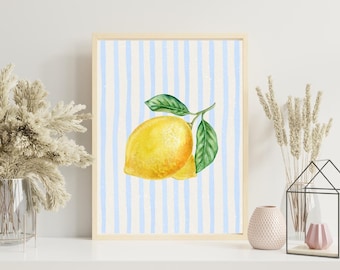 Puede incluir: Una impresión en acuarela enmarcada con dos limones amarillos con hojas verdes sobre un fondo a rayas azules y blancas. La obra de arte está en un marco de madera clara, adecuada para la decoración de la cocina o el comedor.