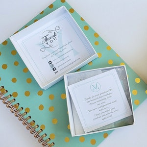 May include: A white box with a thank you note inside. The note says "You have a unique handmade piece. 925 sterling silver." and includes social media handles and an email address. The box is sitting on a teal and gold polka dot surface.