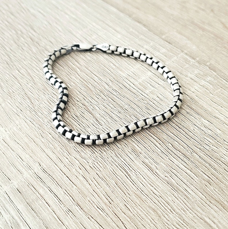 May include: A silver chain bracelet with a box chain design.