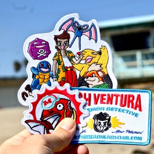 Puede incluir: Un conjunto de parches bordados que representan a un personaje de dibujos animados con un grupo de Pokémon, entre ellos un Squirtle, un Zubat, un Gengar, un Pikachu y un Growlithe. Los parches son blancos con bordados de colores. Los parches están sobre un fondo azul y blanco con el texto "Josh Ventura Pokemon Detective - Your Pokemon - TheDeadHeadsClub.com".