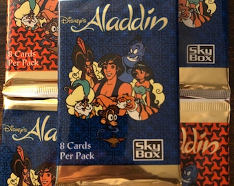 May include: A pack of Disney's Aladdin trading cards featuring Aladdin, Jasmine, Abu, and Jafar. The pack is gold and blue with the text "Disney's Aladdin" and "8 Cards Per Pack" and "Sky Box".