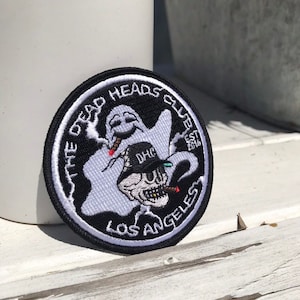 Puede incluir: Parche bordado en blanco y negro con un fantasma fumando un cigarrillo, una calavera con un sombrero fumando un puro y el texto "The Dead Heads Club Est 2018 Los Angeles".