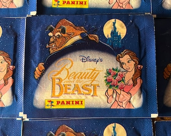 Op de afbeelding: Een blauwe en gele stickerverpakking voor Disney's Belle en het Beest met de personages Belle en het Beest. De stickerverpakking is van Panini.