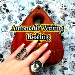 Puede incluir: Una tabla Ouija de madera con las palabras "Automatic Writing Reading" en amarillo y negro. La tabla es sostenida por una mano que lleva dos anillos plateados con piedras negras. El fondo presenta un patrón de calaveras, rosas y mariposas.