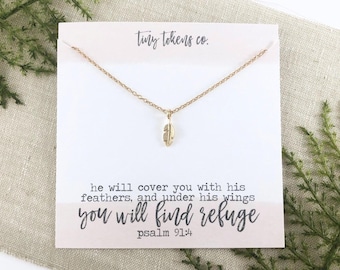 Op de afbeelding: Een roségoudkleurige ketting met een kleine veerhanger bevestigd aan een displaykaart. De kaart bevat de tekst tiny tokens co. bovenaan en het vers he will cover you with his feathers, and under his wings you will find refuge psalm 91:4.
