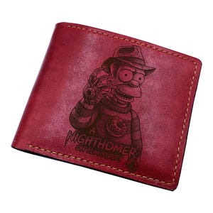 May include: Red leather wallet with a stitched border. The front features a black graphic of a cartoon character in a hat and sweater, holding a bladed glove. The text "A Nighthomer on Elm Street" is below the graphic.