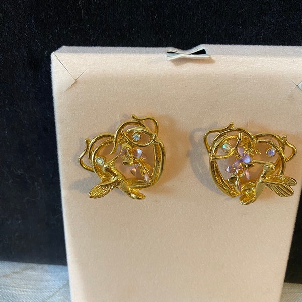 Vintage Kirks Folly heart shaped earrings with gold tone hummingbirds eating nectar from a lavender wisteria flower. AB crystals, signed.