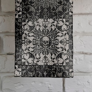 May include: A white brick wall with a wooden shelf holding two glass jars filled with grains and a stack of folded gray fabric. A black and white patterned tea towel hangs from the shelf. A copper pot with a wooden handle hangs from a hook on the wall.