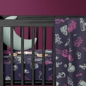May include: A black cot with a white and blue patterned sheet and a matching blanket. The blanket features a design of potion bottles, herbs, and other magical items. A crescent moon shaped pillow is in the cot.