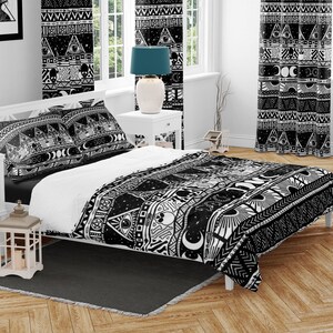 May include: Black and white duvet cover with a geometric pattern featuring moons, stars, eyes, and other mystical symbols. The duvet cover is on a bed with two matching pillowcases.