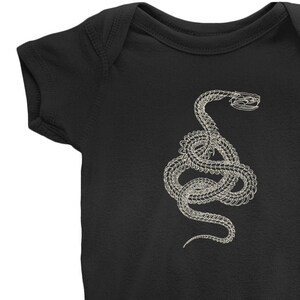May include: A black baby onesie with a white outline of a snake skeleton.