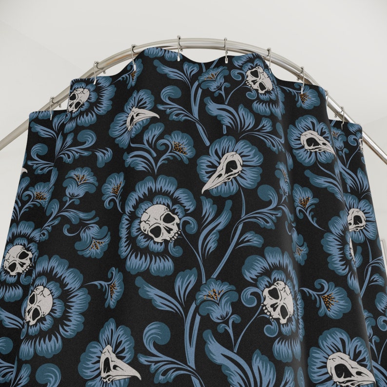Puede incluir: Una cortina de ducha negra con un patr&oacute;n floral azul que presenta calaveras y p&aacute;jaros. El dise&ntilde;o floral es intrincado y detallado, con una est&eacute;tica g&oacute;tica.