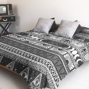 May include: Black and white duvet cover with a geometric pattern featuring moons, stars, and other celestial symbols. The duvet cover is on a bed with two pillows.