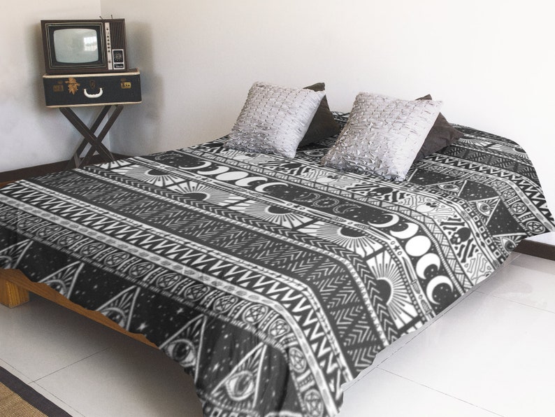 May include: Black and white duvet cover with a geometric pattern featuring moons, stars, and other celestial symbols. The duvet cover is on a bed with two pillows.