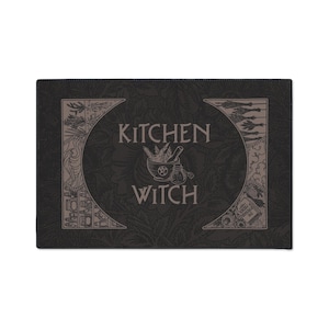 May include: Black and white kitchen witch themed design featuring a mortar and pestle, herbs, and a bottle. The text "Kitchen Witch" is in a decorative font.