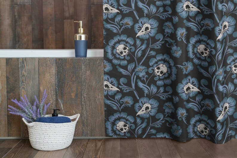 Puede incluir: Una cortina de ducha azul con un patr&oacute;n floral que presenta calaveras blancas y hojas sobre un fondo oscuro.