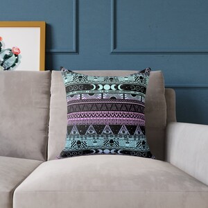 May include: A black and blue throw pillow with a geometric pattern featuring skulls, moons, and eyes. The pattern is repeated in a horizontal stripe design.