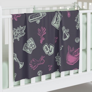 May include: A dark purple baby blanket with a repeating pattern of green and pink illustrations of herbs, potions, tarot cards, and other witchy symbols.
