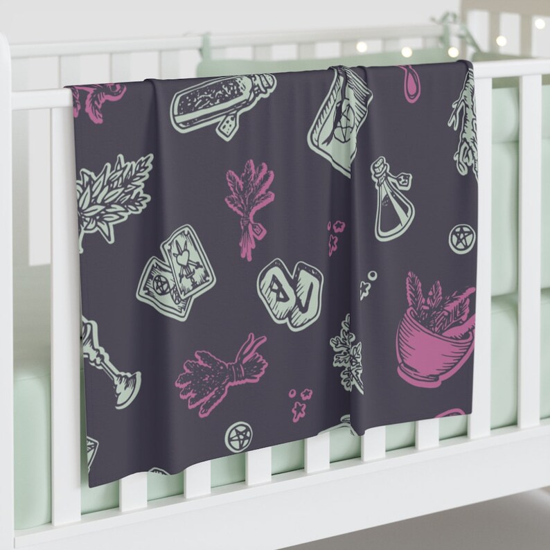 May include: A dark purple baby blanket with a repeating pattern of green and pink illustrations of herbs, potions, tarot cards, and other witchy symbols.
