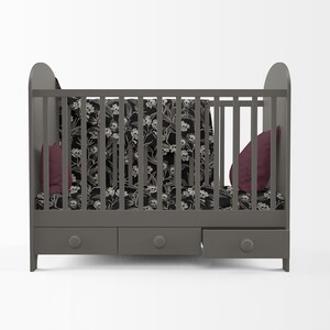May include: A gray crib with a black and white floral print bedding set and two burgundy pillows. The crib has three drawers underneath.