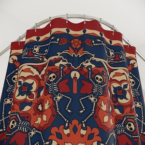 Op de afbeelding: Een douchegordijn met een blauw en rood patroon met skeletten die dansen rond een kaars. Het patroon doet denken aan traditionele Mexicaanse volkskunst.