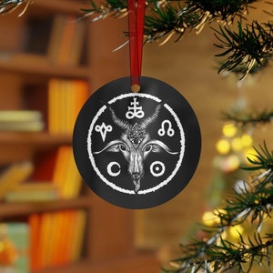 May include: Black and white Christmas ornament featuring a goat head with horns and a pentagram. The goat head is surrounded by a circle with symbols and the words "CO" and "O".