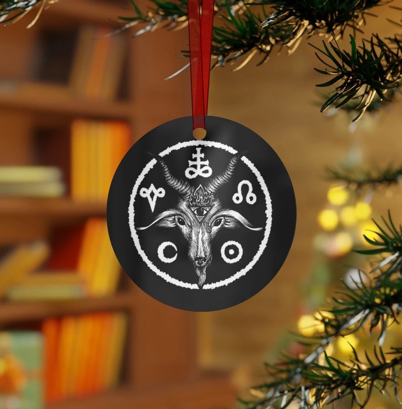 May include: Black and white Christmas ornament featuring a goat head with horns and a pentagram. The goat head is surrounded by a circle with symbols and the words "CO" and "O".