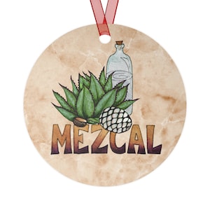 May include: A round, brown, textured ornament with a green agave plant, a clear glass bottle, and a brown pinecone. The word "MEZCAL" is written in black and purple letters.