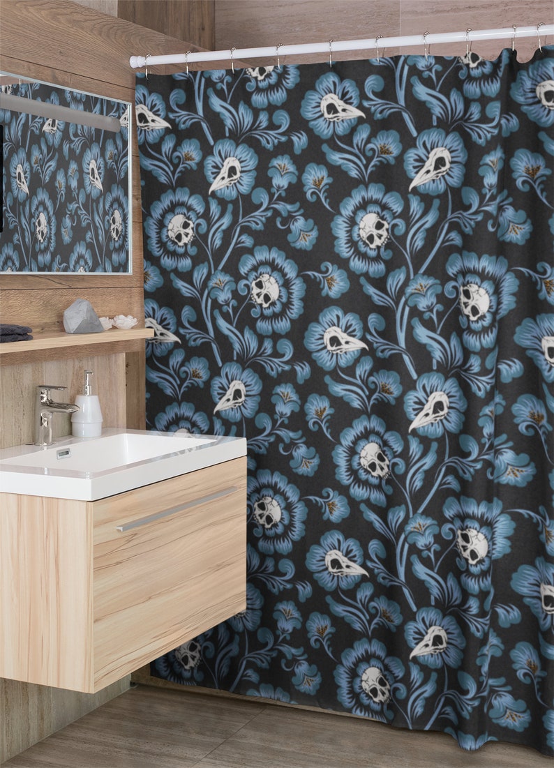 Puede incluir: Una cortina de ducha con fondo azul oscuro y un patr&oacute;n repetido de calaveras blancas y flores azules.