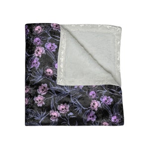 Crushed velvet blanket with purple skull flowers and grey interior.