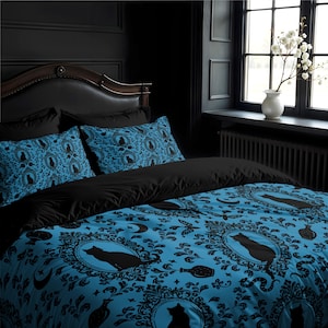 Op de afbeelding: Een blauwe en zwarte beddengoedset met een herhalend patroon van zwarte katten, manen en flessen. De beddengoedset bevat een dekbedovertrek, twee kussenslopen en een decoratief kussen.