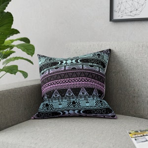 May include: A black and white throw pillow with a colorful geometric pattern featuring moons, stars, eyes, and skulls. The pattern is in shades of pink, blue, and white.