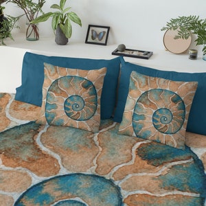 May include: A teal blue bedding set with a large, abstract, watercolor-style print of a nautilus shell. The bedding set includes two pillowcases with a smaller print of the nautilus shell.