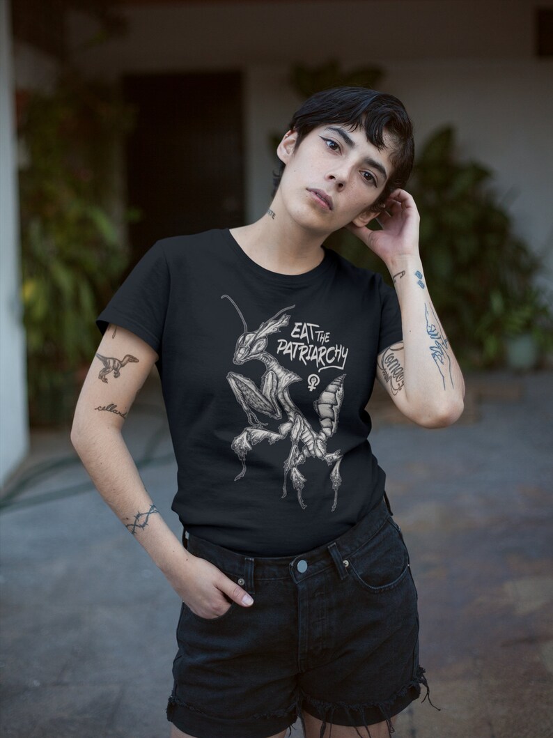 Może przedstawiać: Czarny T-shirt z grafiką modliszki i tekstem "Eat the Patriarchy".