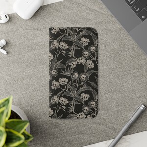 May include: A black phone case with a white floral pattern featuring skulls. The flowers are stylised and have a vintage look.