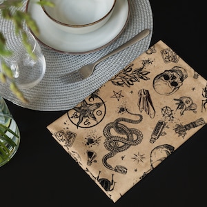 May include: A brown paper wrapping paper with a black and white print of various occult symbols, including a pentagram, a snake, a goat head, and a skull. The paper is on a black surface.