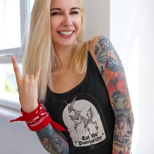 Może przedstawiać: Czarny top na ramiączkach z grafiką modliszki i tekstem "Eat the Patriarchy". Modelka nosi top i ma czerwoną chustkę na nadgarstku.