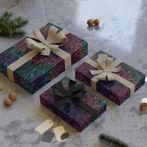 K&ouml;nnte beinhalten: Drei Geschenkboxen, die in schwarzes Papier mit einem Regenbogenmuster aus Katzen eingewickelt sind. Die Boxen sind mit braunem und schwarzem Band gebunden.