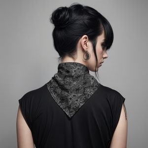 May include: A black bandana with a gray skull and floral pattern. The bandana is tied around the neck of a person with black hair.