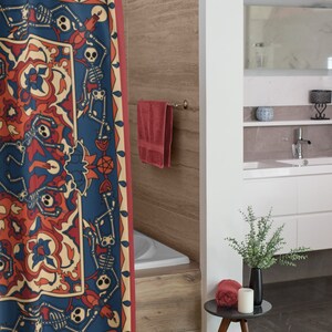 Op de afbeelding: Een rood douchegordijn met een blauw en wit patroon met skeletten die dansen rond een centraal motief. Het gordijn hangt in een badkamer met een wit bad en een houten vloer.