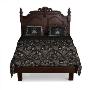 May include: A black and gold duvet cover featuring a geometric pattern of moths, moons, and stars. The duvet cover is on a dark wood bed frame with two matching pillowcases.