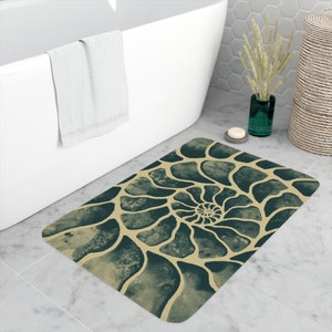 May include: A bath mat with a spiral pattern in shades of green and beige. The pattern resembles a nautilus shell.